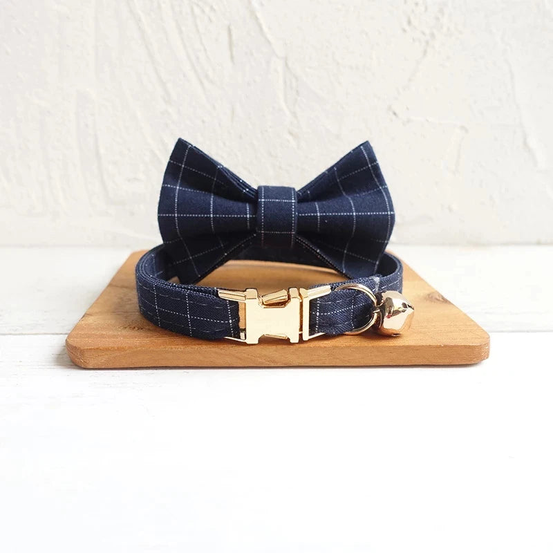 Navy blue plaid dog collar with a bowtie , gold buckle and a bell.