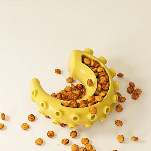 Yellow dental dog toy shaped like a banana with kibble inside on a beige background