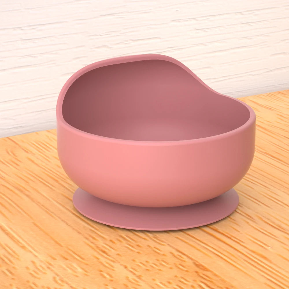 Pink silicone bowl with suction cup on a wooden surface