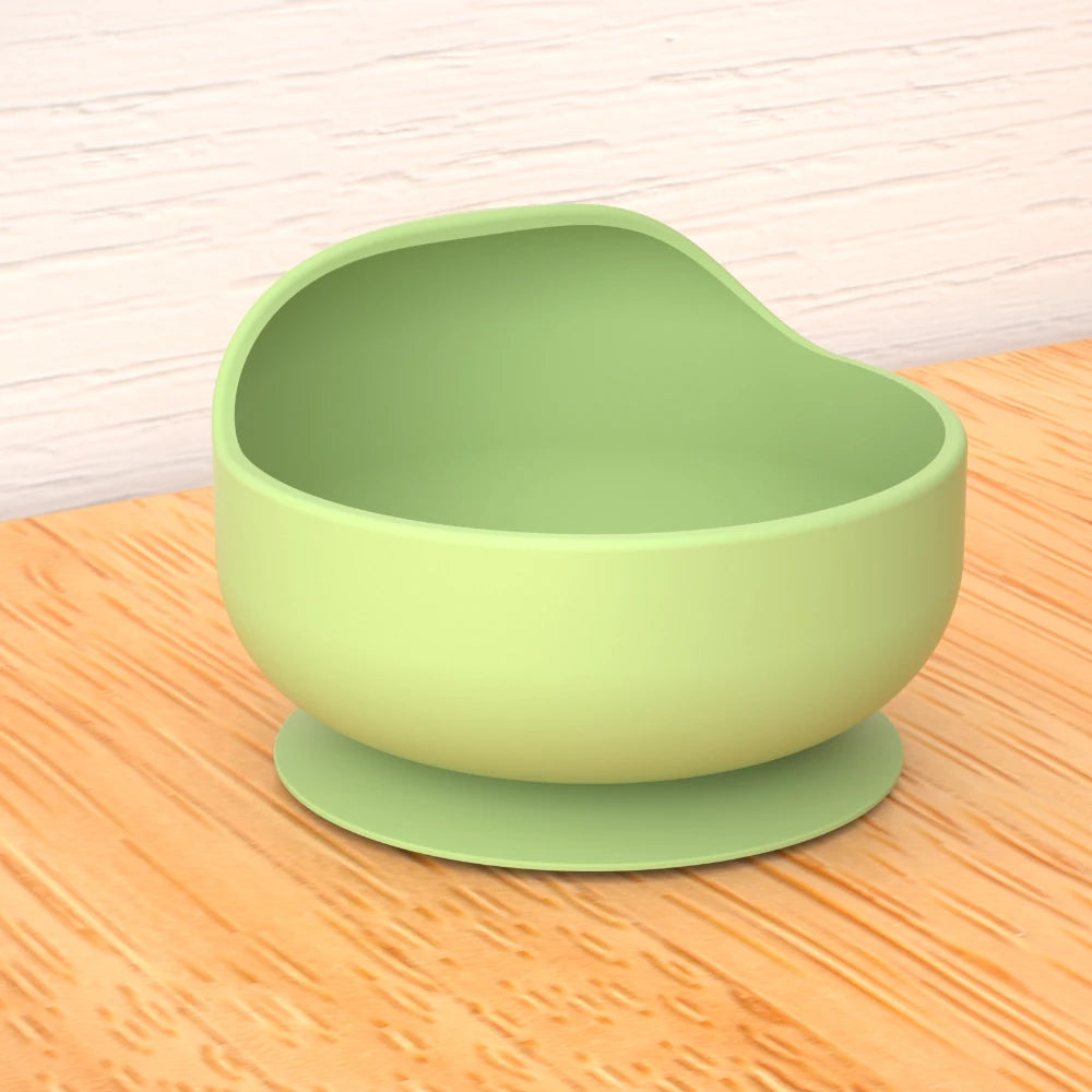 Green silicone suction cup bowl on a wooden surface