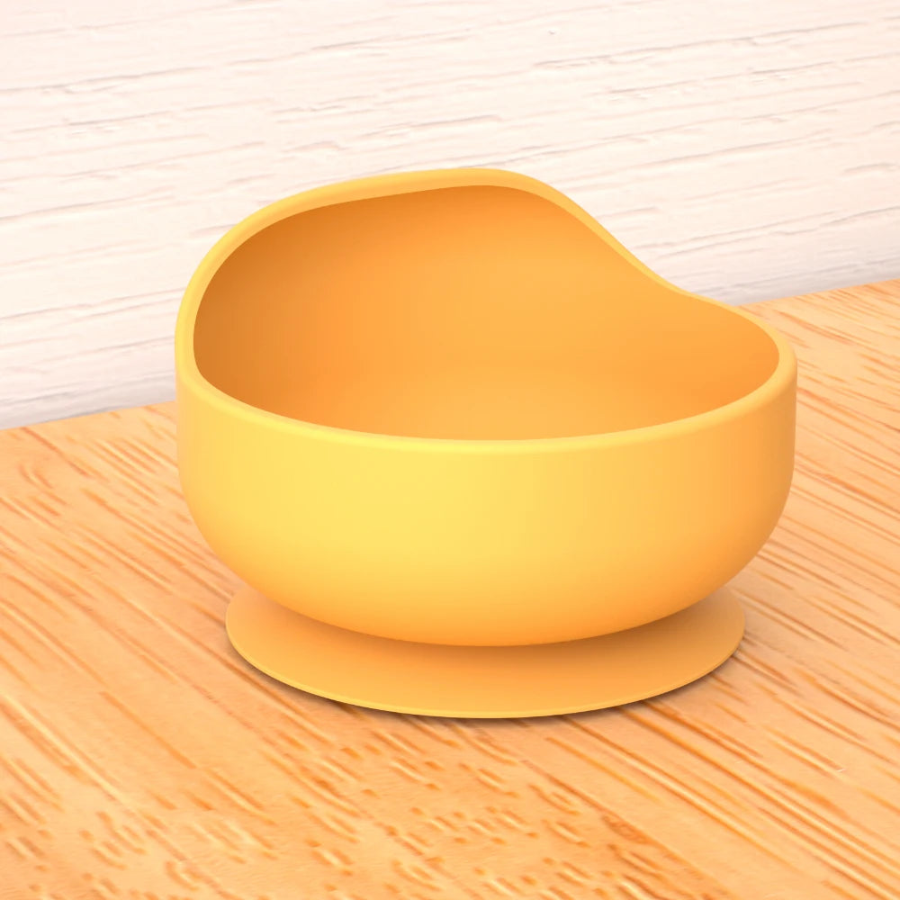 Yellow bowl with suction cup on a wooden surface