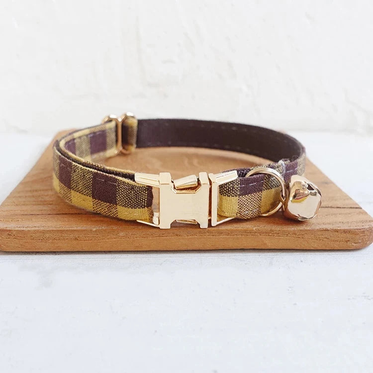 Brown plaid dog collar with golden buckle and bell attachment.