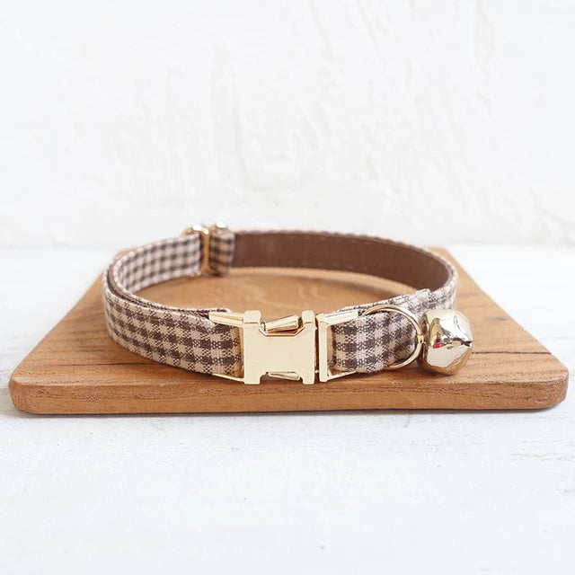 Adjustable brown plaid pet collar with stainless steel buckle and bell attachment.