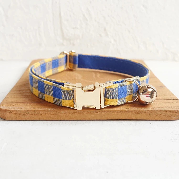 Blue and yellow checkered dog collar with a gold buckle and bell.