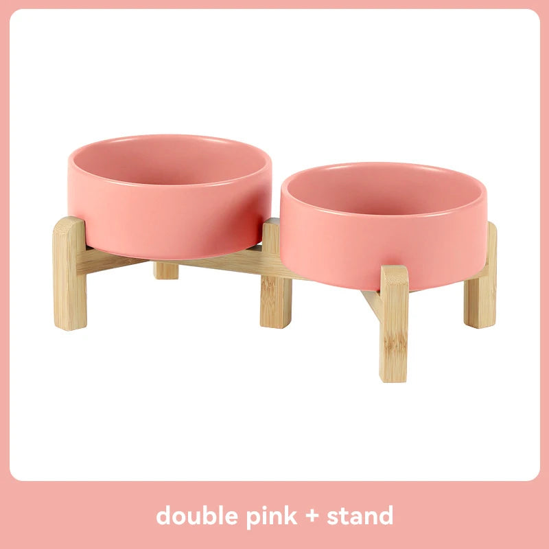 Double pink pet feeder with wooden stand on a white background