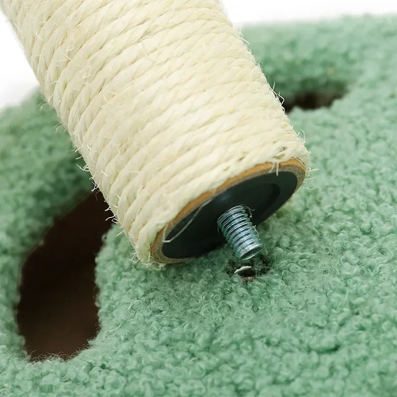 Close-up of a scratching post being screwed into a green carpeted base.