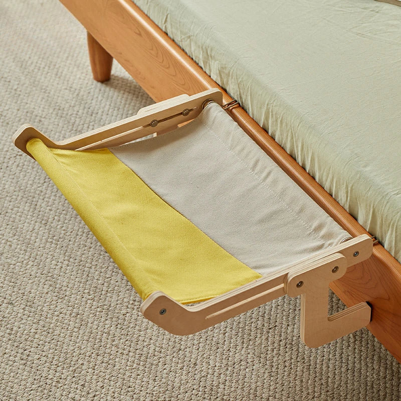 Yellow and white fabric pet hammock mounted under wooden bed.