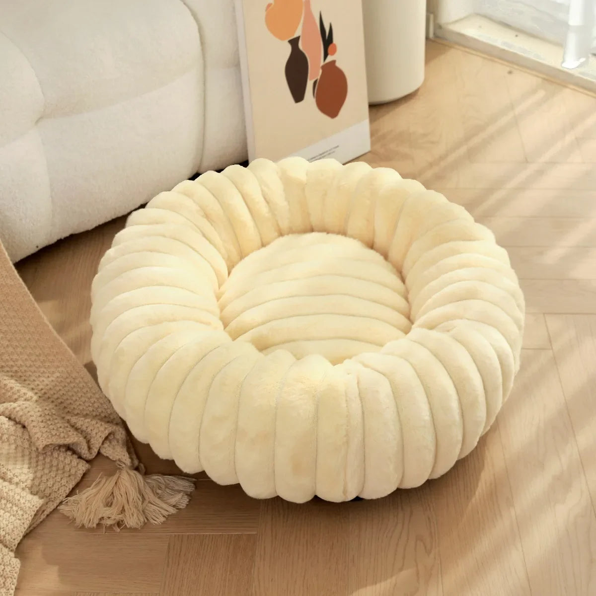 Yellow Round, plush pet bed on a wooden floor with a couch and decorative items in the background.