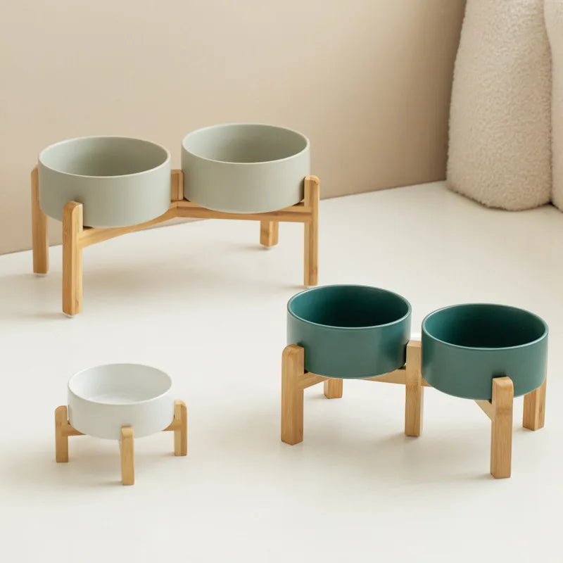 Set of elevated pet ceramic bowls with wooden stands on a neutral background