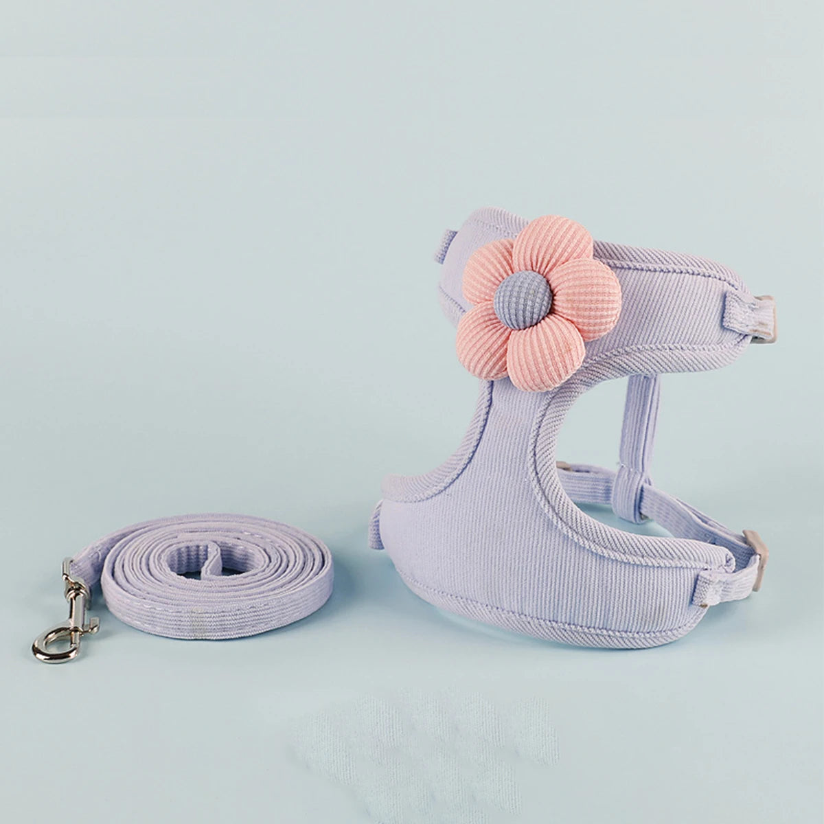 Padded pet harness with pink flower and matching leash on a light purple