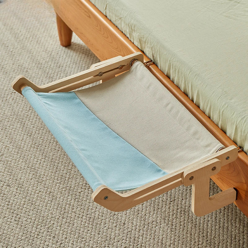 Blue and white fabric pet hammock hanging from wooden bed frame.