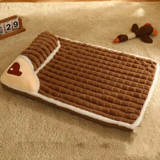 Brown plush dog bed with pillow design placed on carpeted floor.