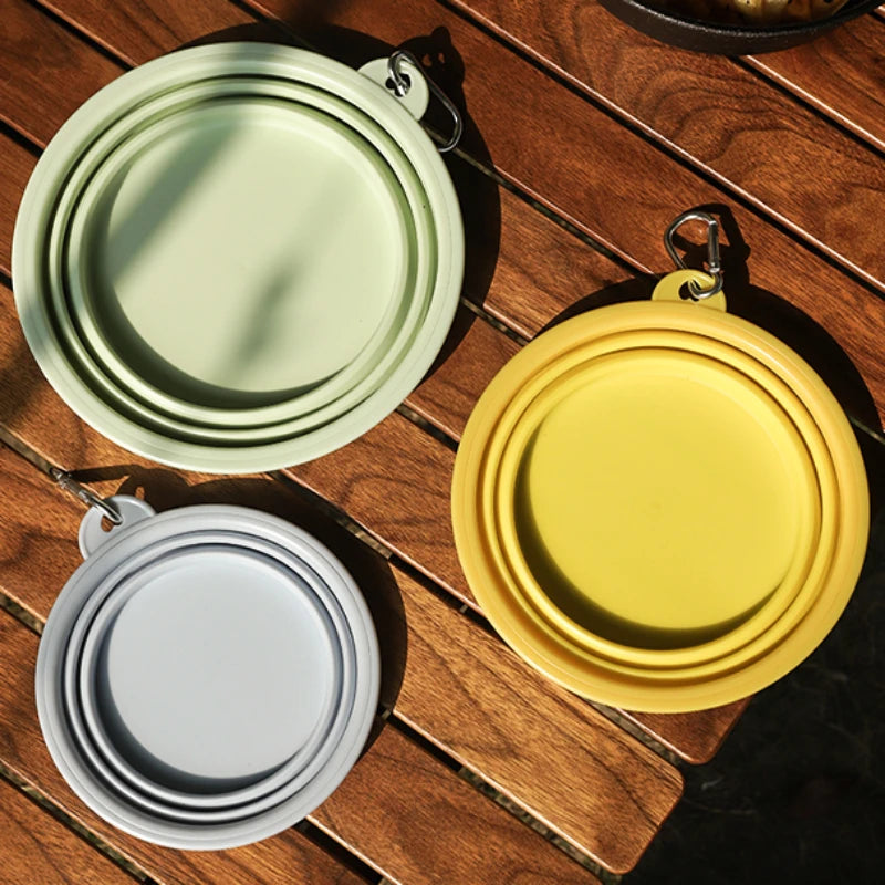 GoBowl™ collapsible silicone pet bowl in green, yellow & light blue, folded flat with metal clip.