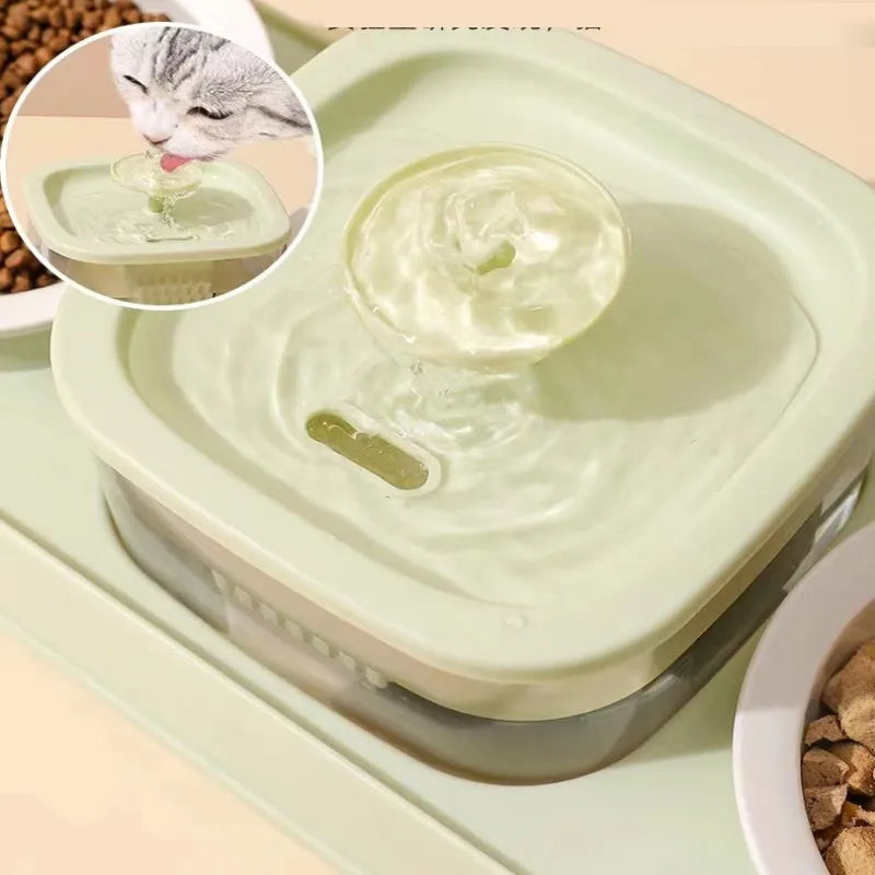 Cat drinking from green pet water fountain with tilted food bowl nearby.