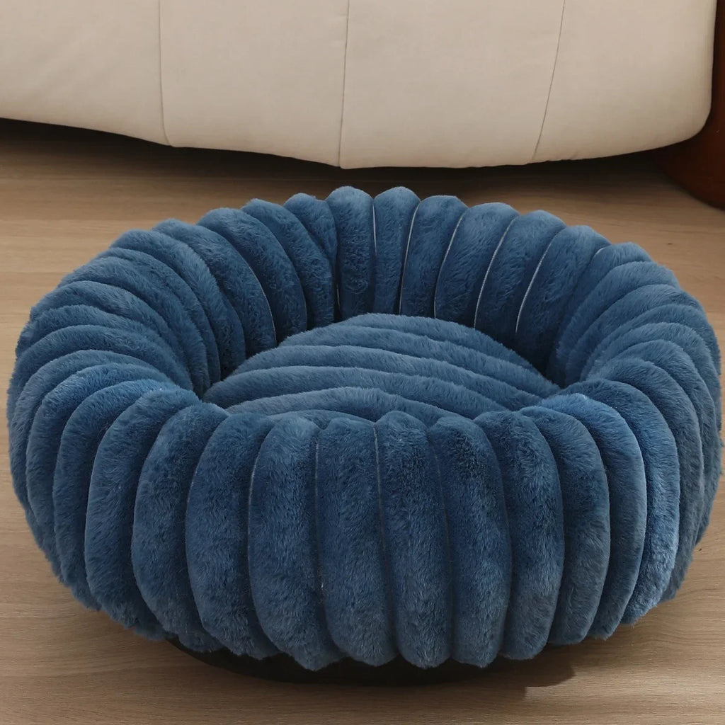 Navy Blue ribbed pet bed on a wooden floor with a beige sofa in the background