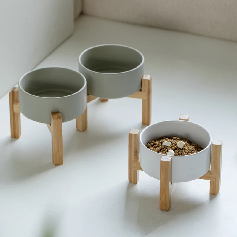 2 ceramic pet bowls with wooden stands on a light surface