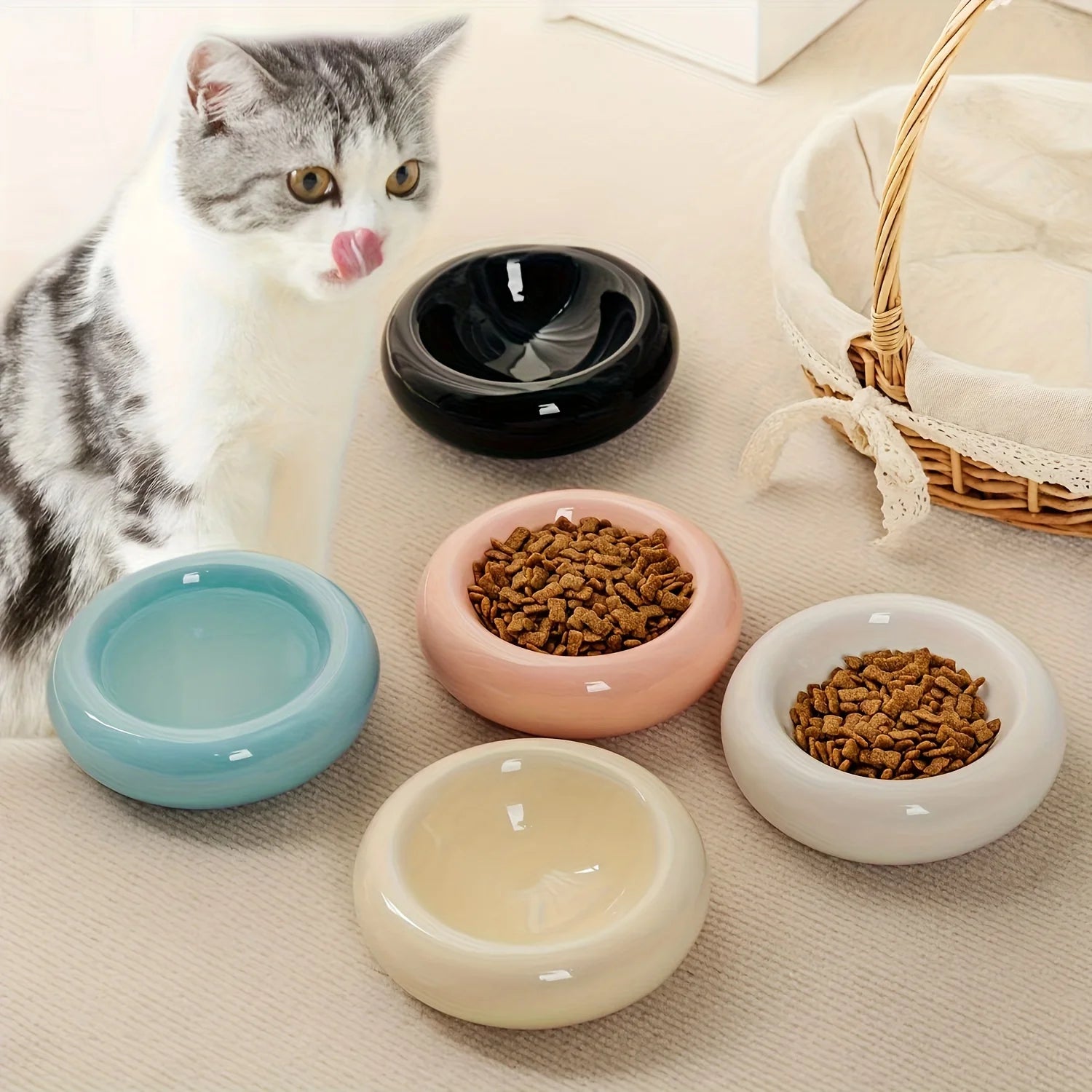 Cat sitting next to colorful ceramic bowls on a beige surface