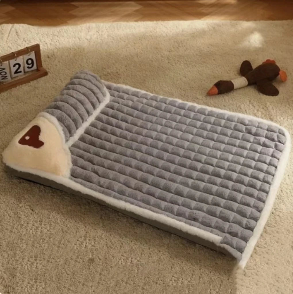 Gray memory foam dog bed with quilted design and built-in pillow on floor.
