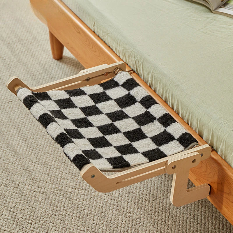 Black and white checkered pet hammock attached to wooden bed frame.