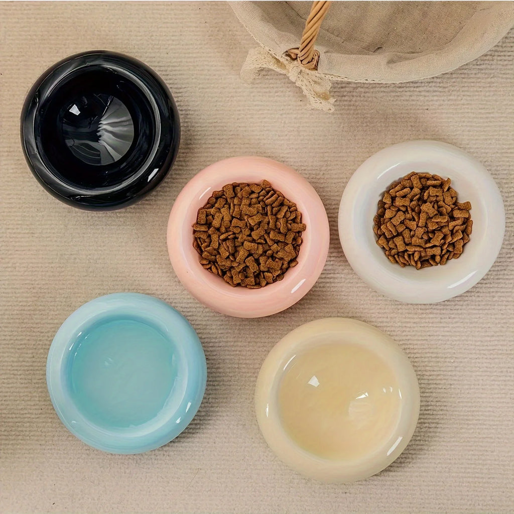 Top view of colorful ceramic bowls with pet food on a textured surface