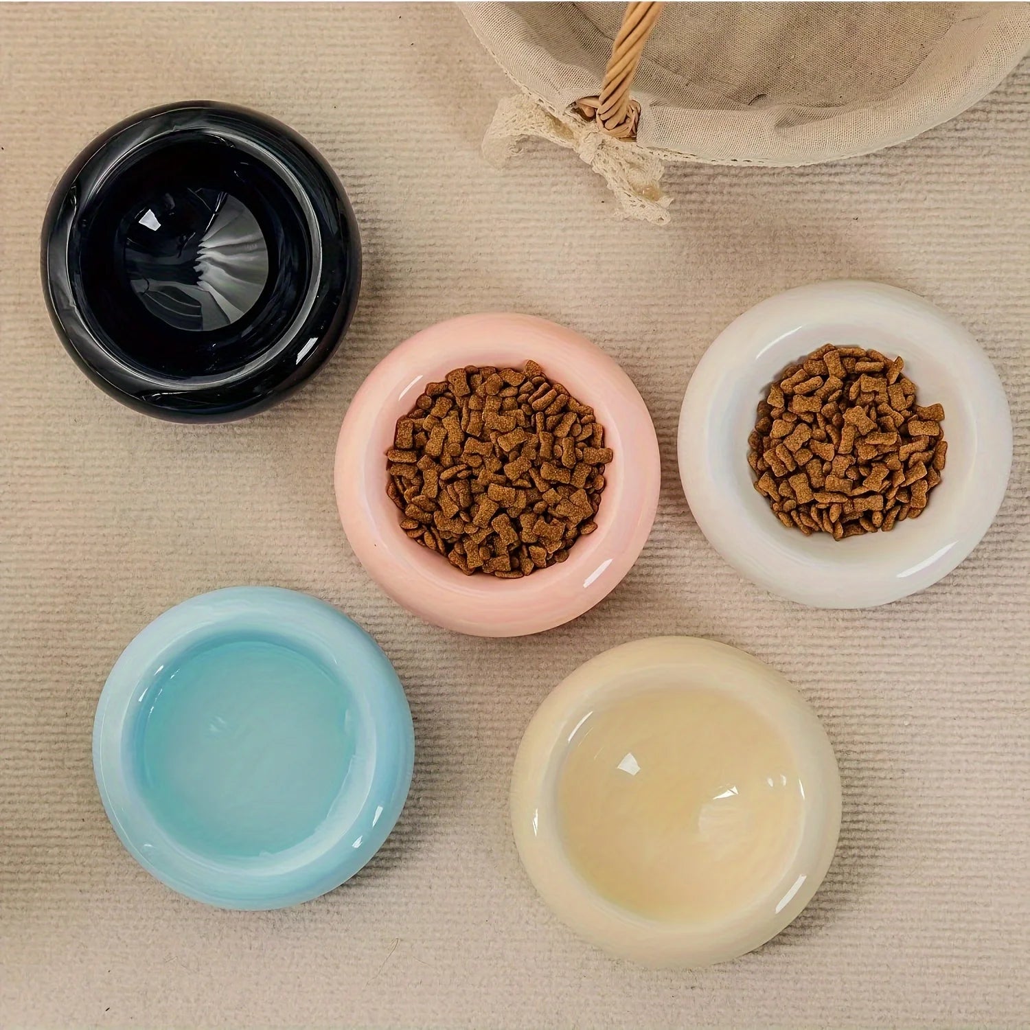 Top view of colorful ceramic bowls with pet food on a textured surface