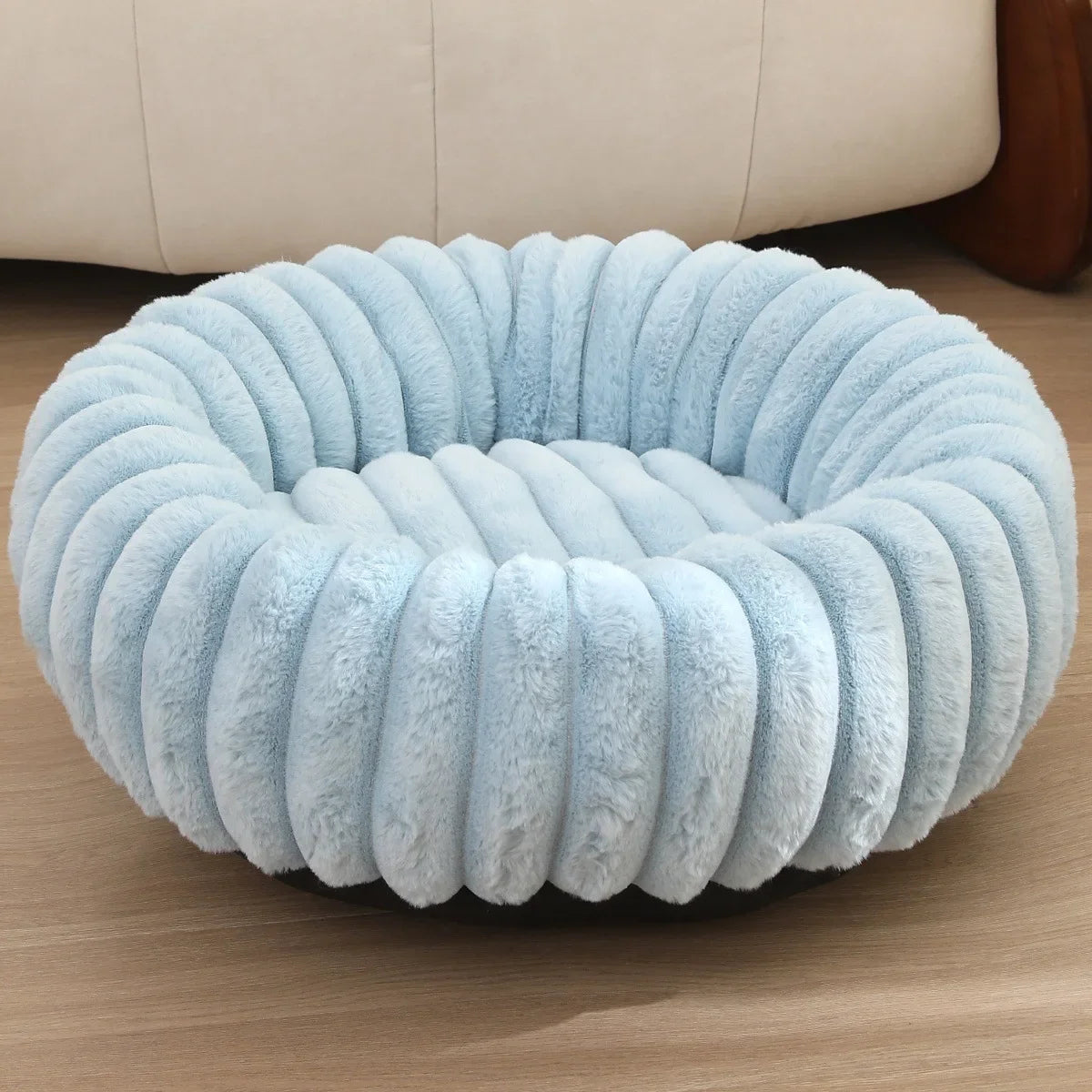 Round, light blue cushion on a wooden floor with a beige sofa in the background