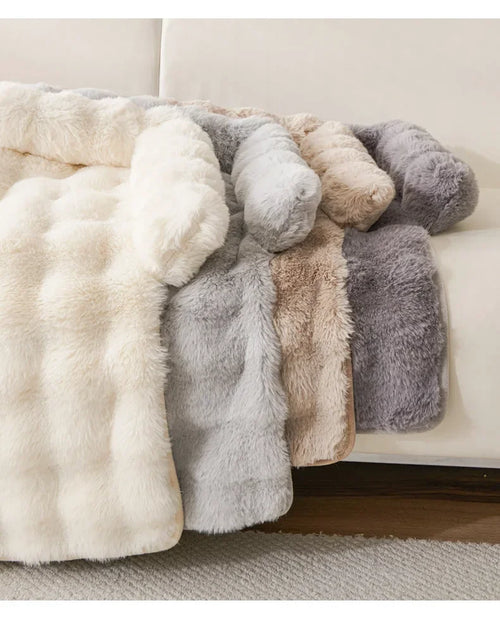Collection of fluffy pet mat beds in various colors on a couch.