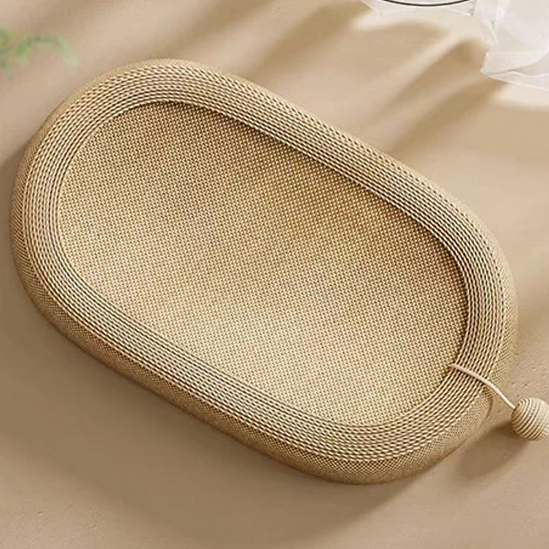 Beige oval cat scratcher bed with textured surface and toy ball attached