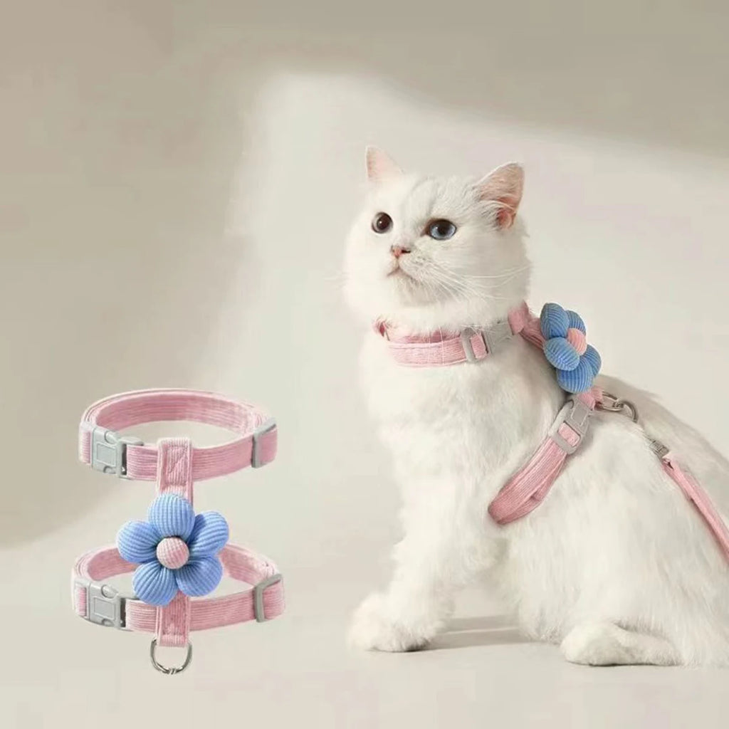 White cat modeling L-shape pink pet harness with blue flower decoration and matching leash.