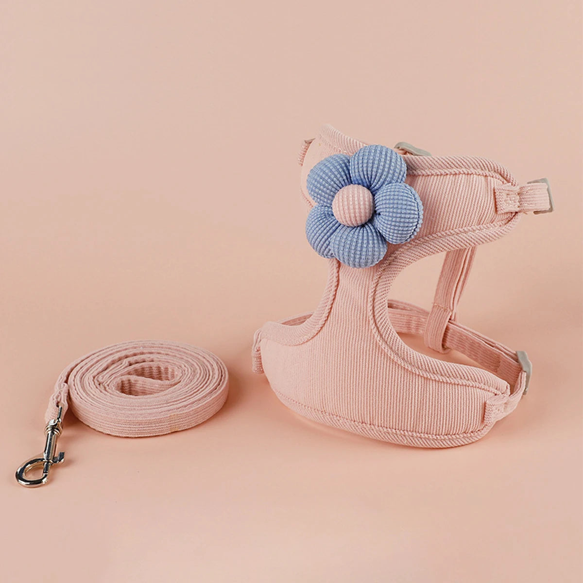 Pink dog padded harness with a blue flower and matching leash on a pink background
